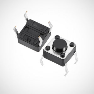 Puede incluir: Dos interruptores de botón pulsador negros con contactos de metal plateado. El interruptor de la izquierda tiene el número "21" impreso. El interruptor de la derecha tiene un botón negro.