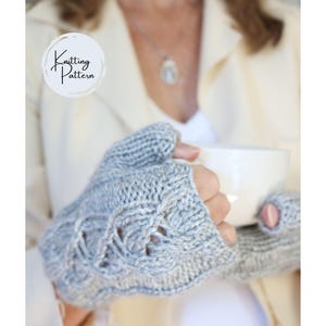 May include: A pair of light gray fingerless gloves featuring a textured cable knit pattern. The gloves are crafted from yarn and include a circular logo in the upper left corner with the text Knitting Pattern written in black script.