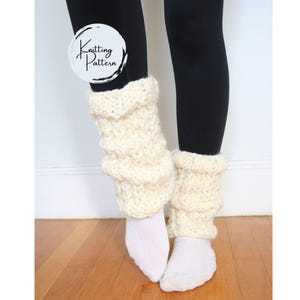 May include: A pair of cream-colored knitted leg warmers with a textured pattern. The leg warmers are worn over white socks and black leggings.