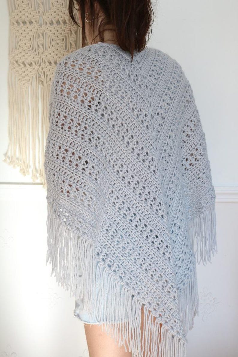 May include: A light gray crochet shawl with fringe. The shawl is made with a delicate open stitch pattern.