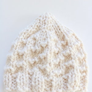 May include: A white knitted beanie hat with a textured pattern.