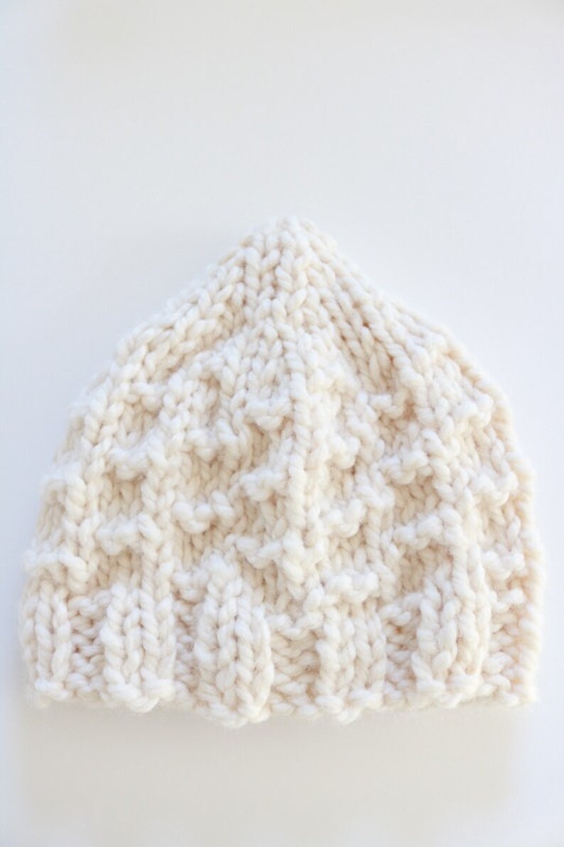 May include: A white knitted beanie hat with a textured pattern.