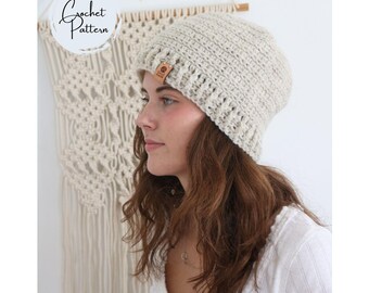 May include: A light beige crochet beanie featuring a textured ribbed brim and a small brown rectangular tag on the side. The text Crochet Pattern is visible in the upper left corner. The beanie has a thick, woven construction with a soft appearance.