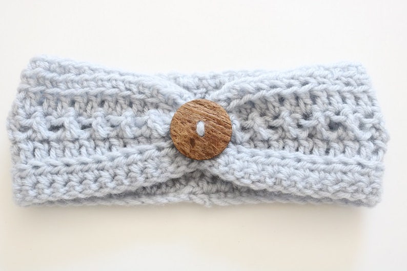 May include: A light blue crocheted headband with a wooden button in the center.