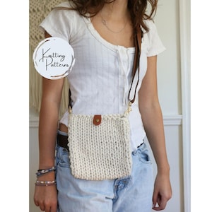 Op de afbeelding: Crèmekleurige, gebreide crossbodytas met een bruine leren riem en een knoopsluiting. De tas is rechthoekig en heeft een getextureerde uitstraling. De tas wordt over de schouder gedragen. De tas heeft een goudkleurige sluiting.