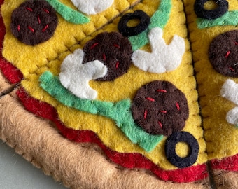 May include: A felt pizza with a brown crust, red sauce, yellow cheese, green peppers, white mushrooms, and black olives.
