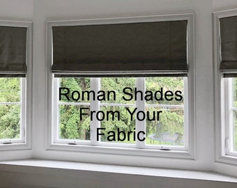 May include: Three windows with gray roman shades, each with a view of green trees and foliage. The text "Roman Shades From Your Fabric" is centered in the middle window.
