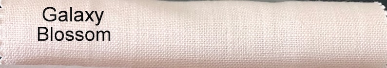 May include: Close-up of a white fabric swatch with the text "Galaxy Blossom" printed on it.