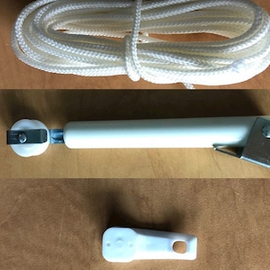 May include: A white rope, a white plastic roller with a metal bracket, and a white plastic handle for a window blind.