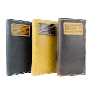 May include: Three leather wallets in black, mustard yellow, and brown. Each wallet features a rectangular patch with an American flag design and a bull silhouette. The wallets have white stitching around the edges.