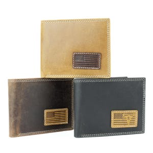 May include: Three leather wallets in shades of tan, brown, and black. Each wallet features a rectangular patch with an American flag design. The wallets are rectangular with white stitching around the edges.