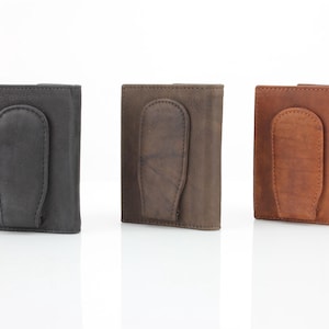May include: Three leather wallets with a money clip. The wallets are in black, brown, and tan.