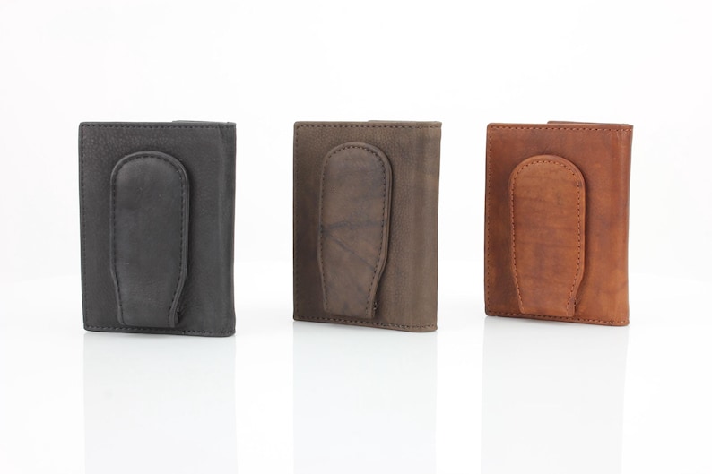 May include: Three leather wallets with a money clip. The wallets are in black, brown, and tan.