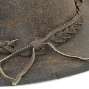 Pu&ograve; includere: Un cappello di pelle marrone con una fascia in pelle intrecciata e una cravatta in pelle. Il cappello ha un aspetto vissuto ed &egrave; fatto di una pelle morbida e flessibile.