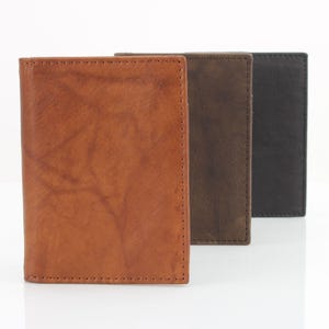 May include: Three leather wallets in different colors: brown, dark brown, and black. The wallets are lined up in a row, with the brown wallet in the front.