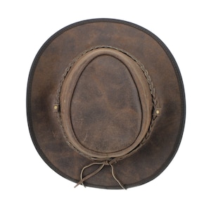 Pu&ograve; includere: Un cappello da cowboy in pelle marrone con una fascia in pelle intrecciata e un cinturino per il mento in pelle marrone.