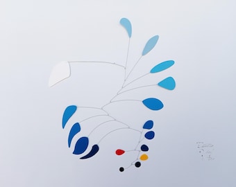 May include: A mobile sculpture with blue, red, yellow, and black teardrop-shaped pieces suspended from thin wires. The sculpture is hanging from the ceiling and is in motion. The artist's signature is visible in the bottom right corner.
