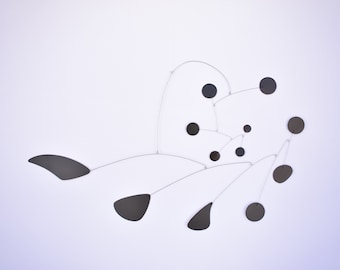 Peut inclure: Une sculpture mobile noire et argentée avec des éléments circulaires et en forme de larme suspendus à de fins fils.