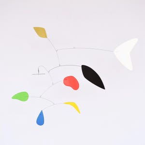 Può includere: Un mobile colorato con forme nere, bianche, rosse, gialle, verdi e blu appese a una struttura in filo d'argento.