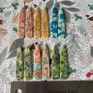 May include: Six pairs of colorful, marbled, plastic hair clips. The clips are long and narrow, with a pointed end. The colors include pink, yellow, blue, green, and orange.
