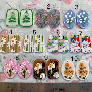Könnte beinhalten: Zehn Paar handgefertigte Ohrringe aus Polymer Clay. Jedes Paar hat ein anderes Design, darunter florale, geometrische und von der Natur inspirierte Muster. Die Ohrringe werden auf einer weißen Oberfläche mit einem Lineal zur Skalierung angezeigt.