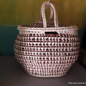 May include: A woven basket with a lid and a handle. The basket is made of brown and white strips of material and has a rounded shape.