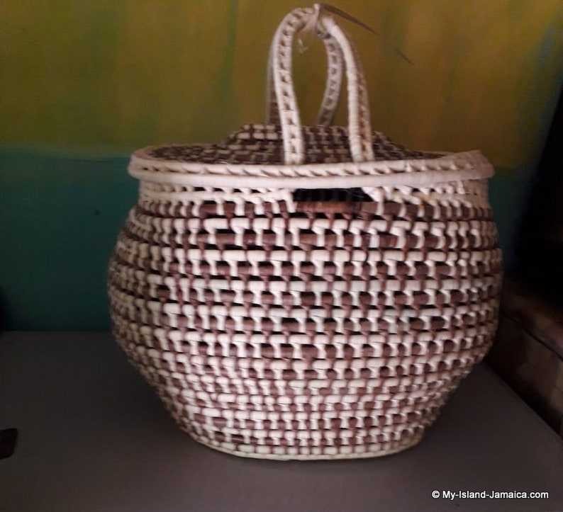 May include: A woven basket with a lid and a handle. The basket is made of brown and white strips of material and has a rounded shape.