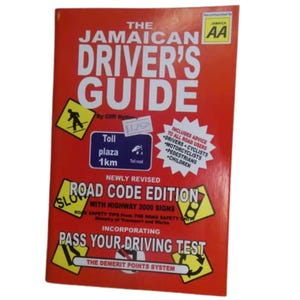 Peut inclure: Un livre rouge intitulé "The Jamaican Driver's Guide" avec du texte et des panneaux routiers. La couverture comprend le texte "Road Code Edition" et "Pass Your Driving Test". Une étiquette indique un prix de 11,50 €.