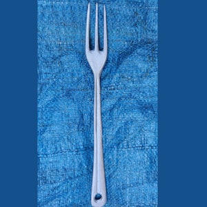 May include: A silver fork with four tines and a long handle. The fork is on a blue textured background.