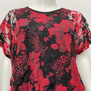 May include: Black and red floral lace top with short sleeves. The top features a round neckline and a layered design. The red floral pattern is prominent against the black lace.