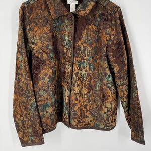 May include: A long-sleeved button-down jacket featuring a textured, multi-colored abstract pattern in shades of dark brown, copper, and teal. The garment has a classic collar, a front button closure, and a straight hemline, hanging on a white hanger.