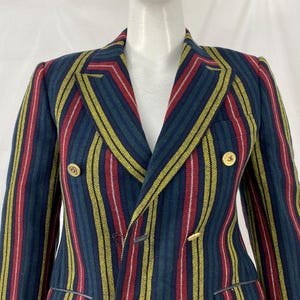 May include: A double-breasted blazer with vertical stripes in navy, red, yellow, and white. The jacket features gold-colored buttons and a notched lapel. The blazer is a classic piece of apparel.