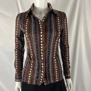 May include: A long-sleeved button-down shirt with a brown, blue, and white vertical stripe pattern. The shirt has a collared neckline and buttoned cuffs. The fabric appears to be a lightweight material.