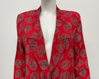 May include: A red blazer with a black and gold dotted pattern. The blazer has a notched collar and long sleeves. The fabric appears to be a lightweight material.