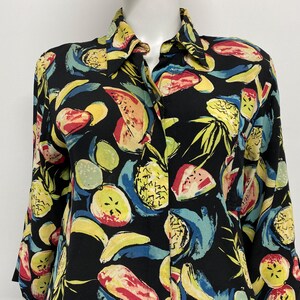 May include: Black button-down shirt with a vibrant fruit pattern. The design features yellow bananas, red watermelon, green limes, and yellow pineapples. The shirt has long sleeves and a classic collar.