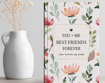 May include: A white journal with a floral pattern and the text "You + Me Best Friends Forever" with a heart symbol. The text "Made With Love By Isabella" is also included.