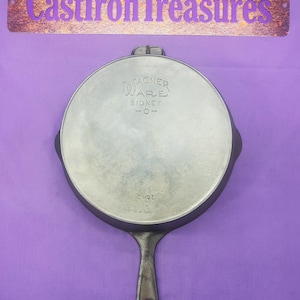 May include: A cast iron skillet with a black handle. The skillet is marked "Wagner Ware Sidney, O-" on the bottom.