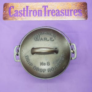 May include: A cast iron Wagner Ware Drip Drop Roaster, No. 6, with a metal handle and lid. The lid has the words "Wagner Ware" and "Drip Drop Roaster" embossed on it. The sign above the roaster reads "Cast Iron Treasures".