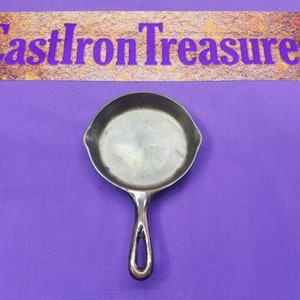 May include: A small, cast iron skillet with a black handle. The skillet is empty and has a smooth, dark surface.