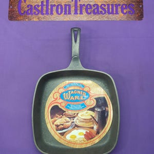 May include: A square, cast iron Wagner Ware skillet with a long handle. The skillet has a dark gray finish and a circular label with images of food. The sign above the skillet reads "Cast Iron Treasures."