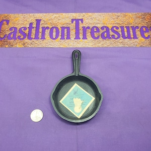 May include: A small black cast iron skillet with a handle. The skillet has a blue and white label that reads "Early American Skillet, 5" As Seen On TV, Made in China".