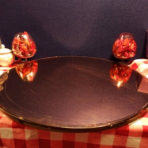 May include: A round, dark brown, mirrored tray with a gold rim sits on a red and white checkered tablecloth. Two clear glass bowls filled with red rose petals are reflected in the tray.
