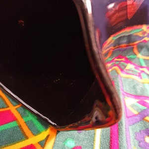 May include: A black ceramic pitcher with a glossy finish. The pitcher is empty and has a wide, rounded opening.