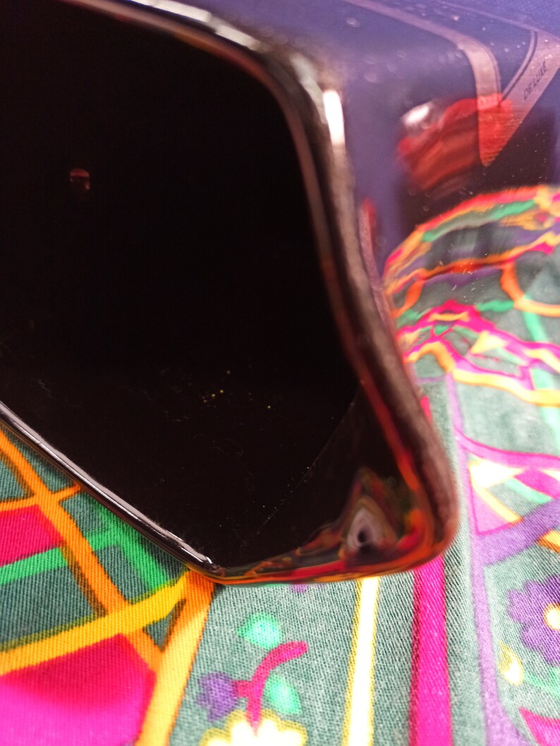 May include: A black ceramic pitcher with a glossy finish. The pitcher is empty and has a wide, rounded opening.