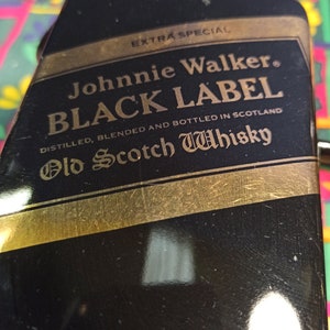 May include: A black bottle with a gold label that reads "EXTRA SPECIAL Johnnie Walker. BLACK LABEL DISTILLED, BLENDED AND BOTTLED IN SCOTLAND Old Scotch Whisky".