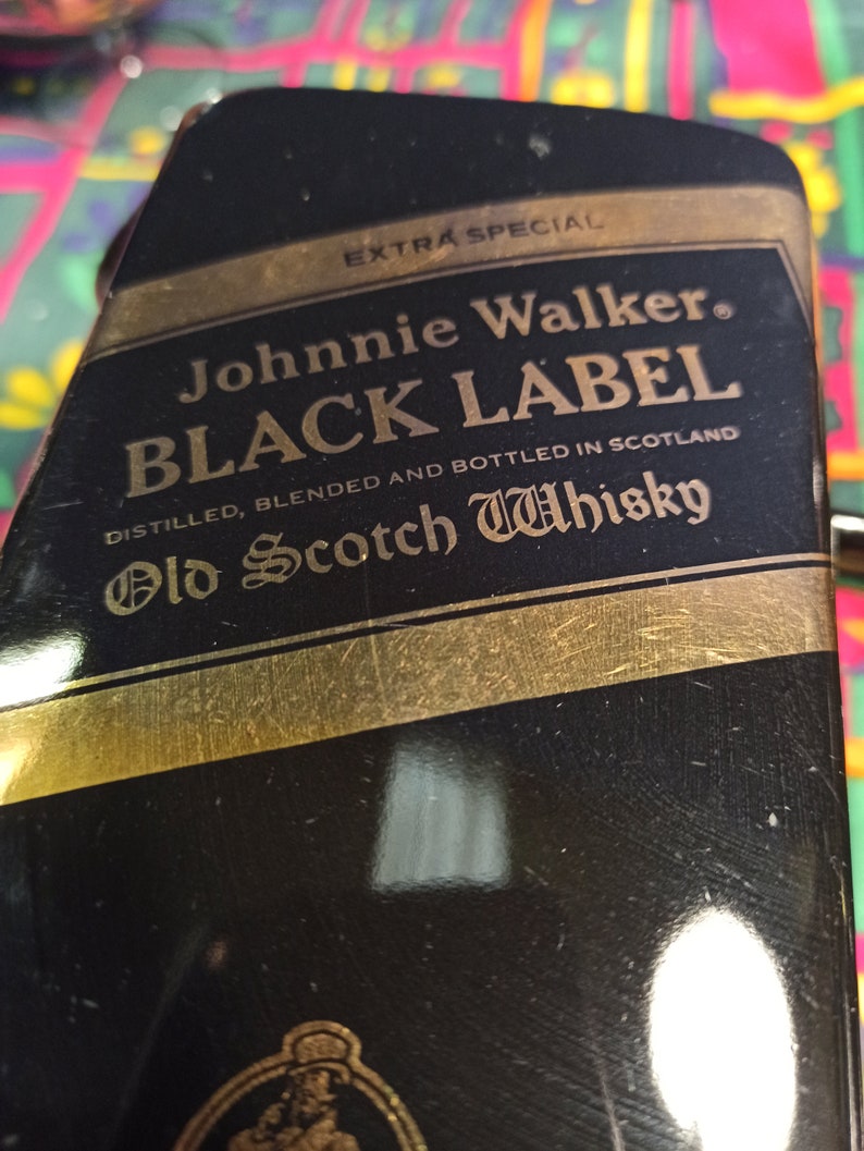 May include: A black bottle with a gold label that reads "EXTRA SPECIAL Johnnie Walker. BLACK LABEL DISTILLED, BLENDED AND BOTTLED IN SCOTLAND Old Scotch Whisky".