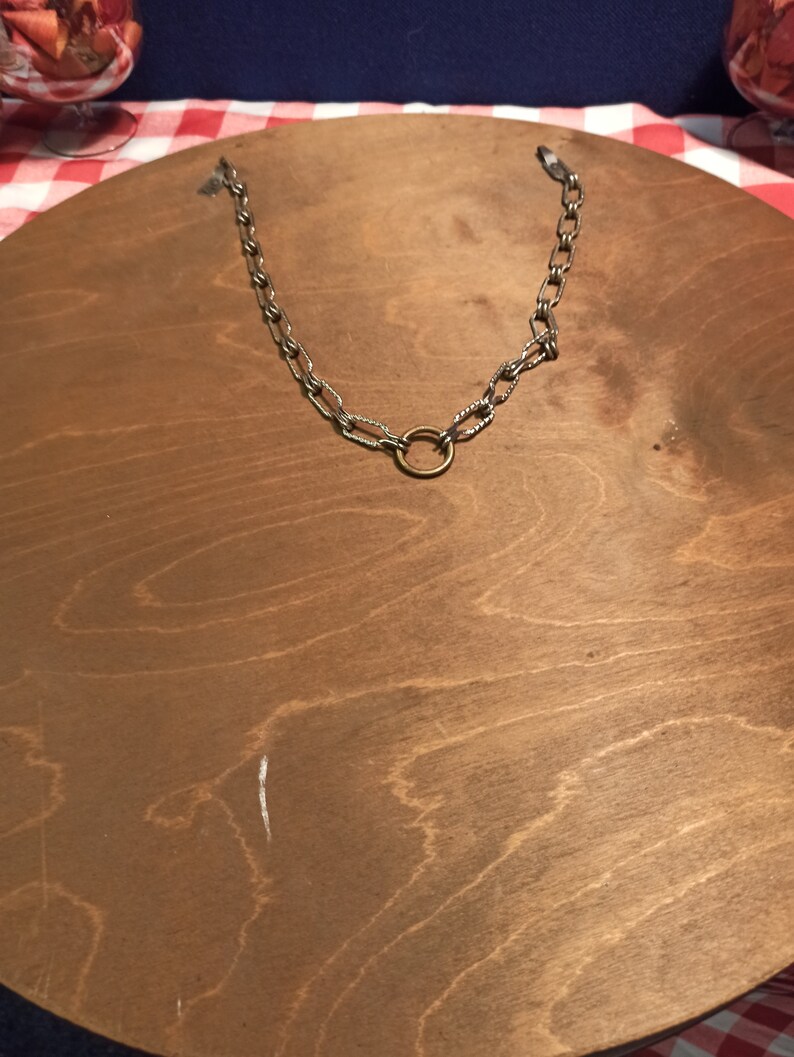 May include: The back of a round wooden wall mirror with a silver chain and a brass ring for hanging.