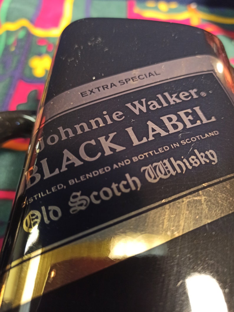 May include: A black bottle with a gold label that reads "EXTRA SPECIAL Johnnie Walker BLACK LABEL" and "DISTILLED, BLENDED AND BOTTLED IN SCOTLAND Old Scotch Whisky".