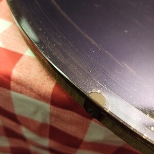 May include: Close-up of a dark purple vinyl record with a black label. The record is on a red and white checkered surface.
