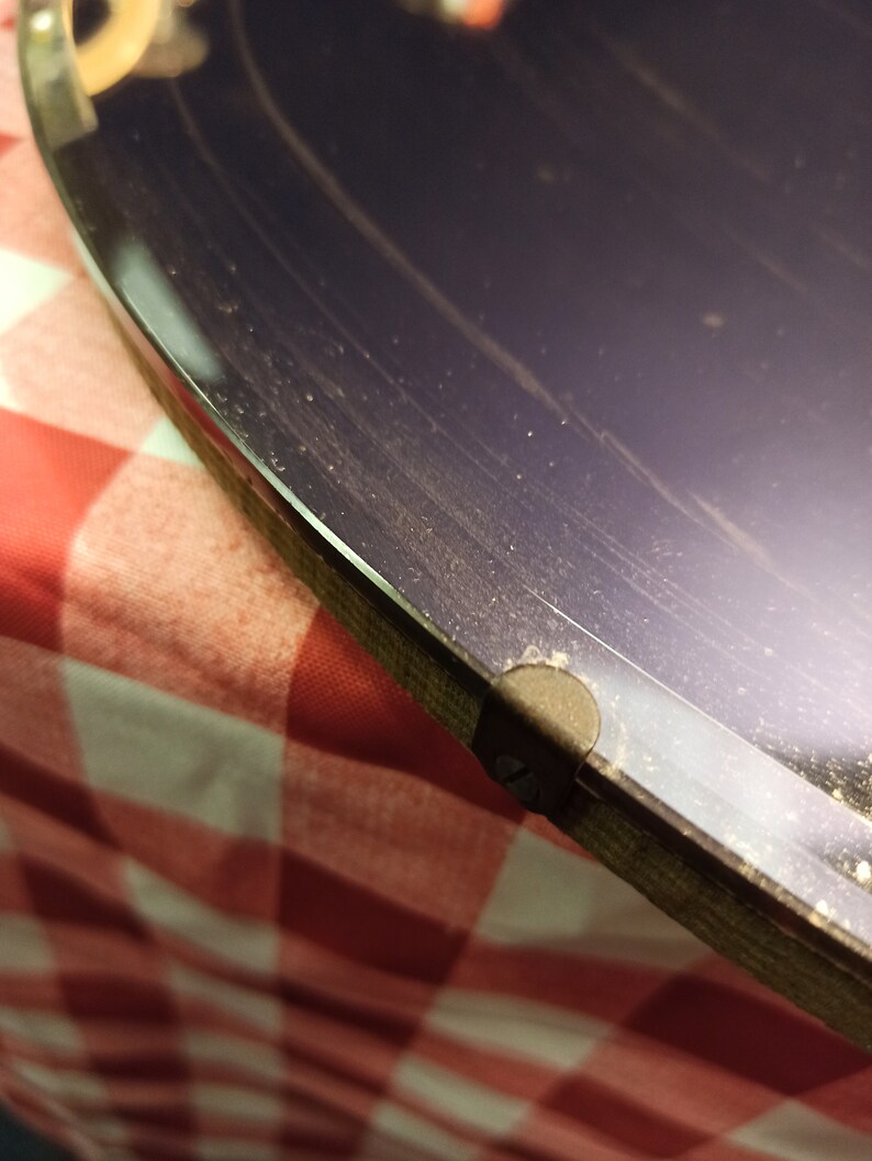 May include: Close-up of a dark purple vinyl record with a black label. The record is on a red and white checkered surface.